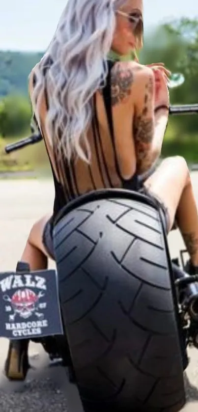 Tattooed woman on motorcycle, scenic backdrop.