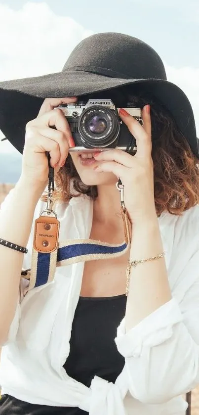 Person with camera and black hat in stylish outdoor scene.