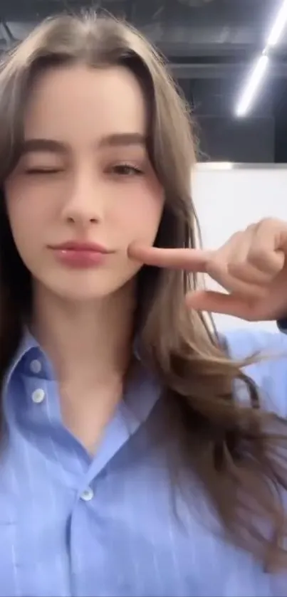 Woman winking with peace sign, blue shirt.