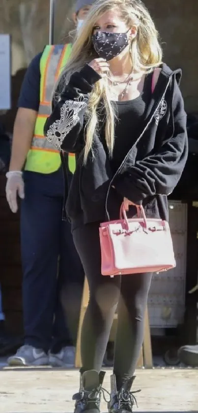 Woman in stylish black outfit with pink bag showcasing urban street style.