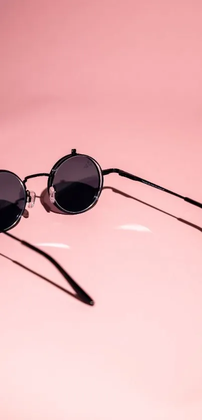 Round sunglasses on pink background mobile wallpaper.