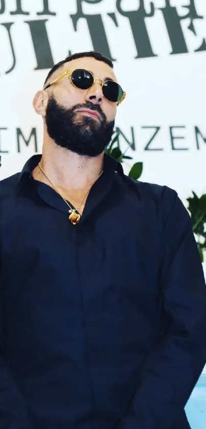 Man in black shirt and sunglasses with stylish minimalist backdrop.