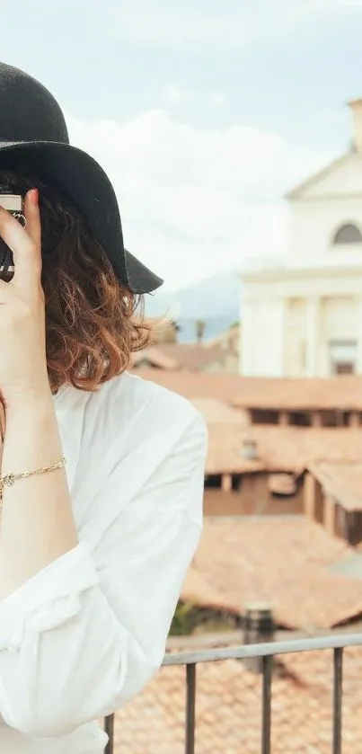 Stylish woman in black hat photographing cityscape.