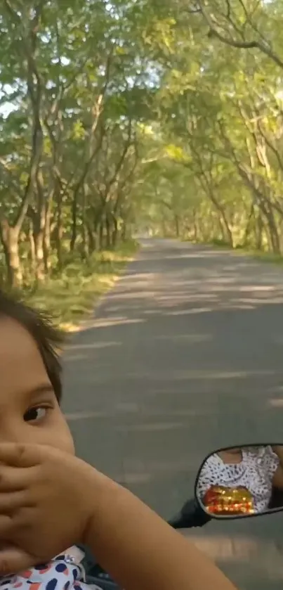 Child enjoys a ride on a tree-lined road.