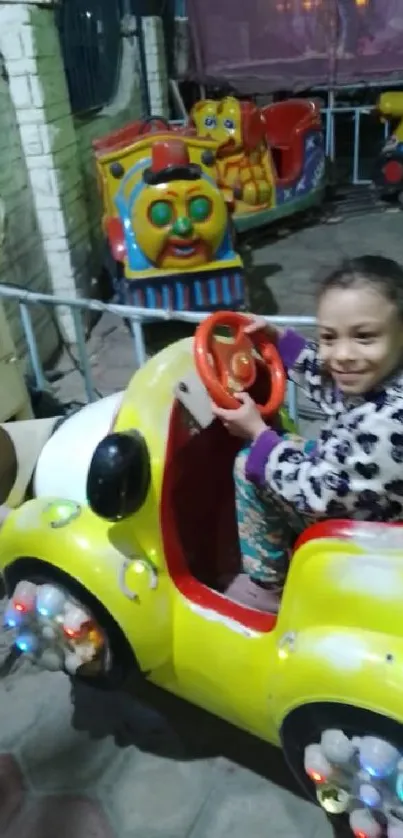 Child enjoying a vibrant yellow car ride in amusement park.