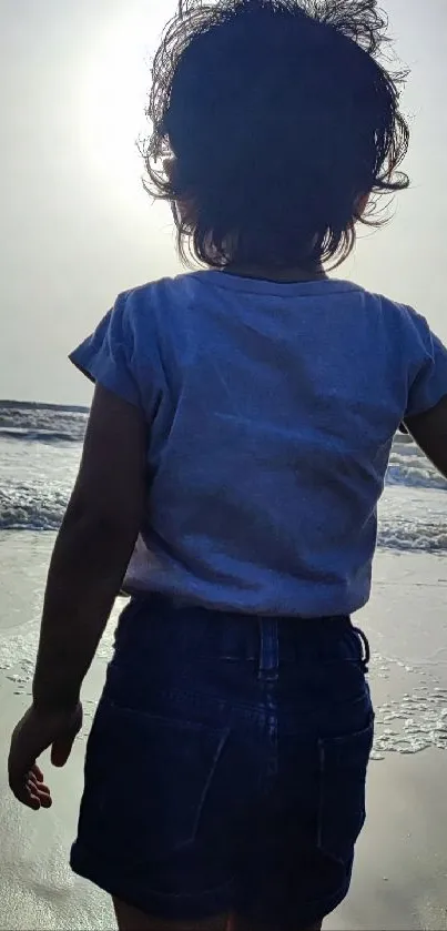 Silhouette of child facing the ocean at sunset.