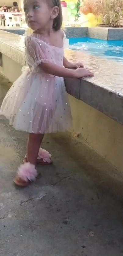 Young child in a dress by the poolside.