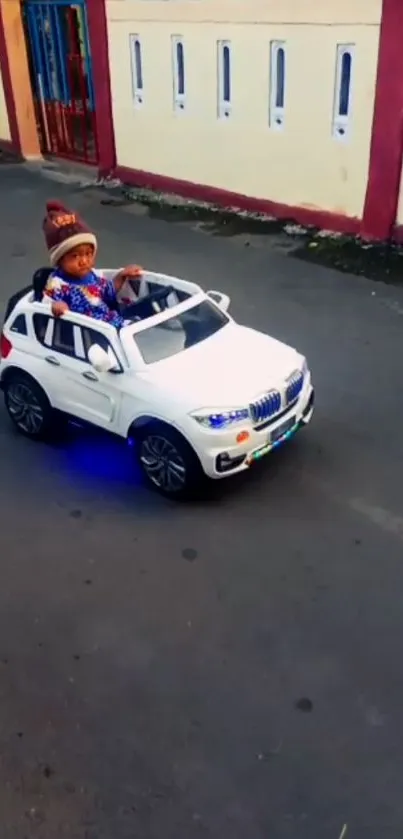 Child drives a white toy car on a street.