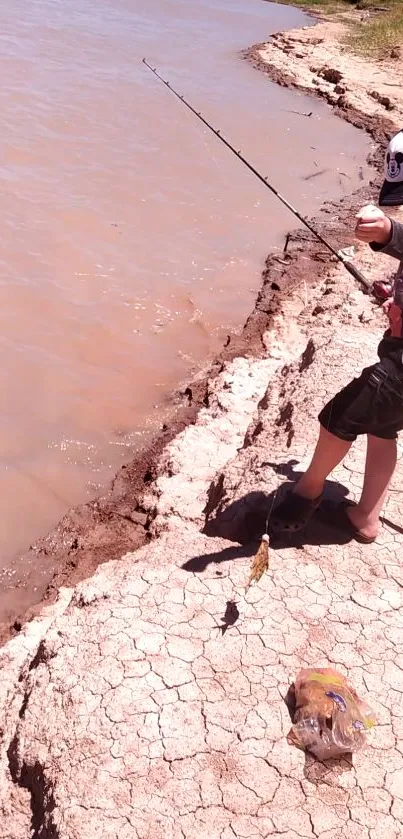 Child fishing on a dry lake shore under the sun.