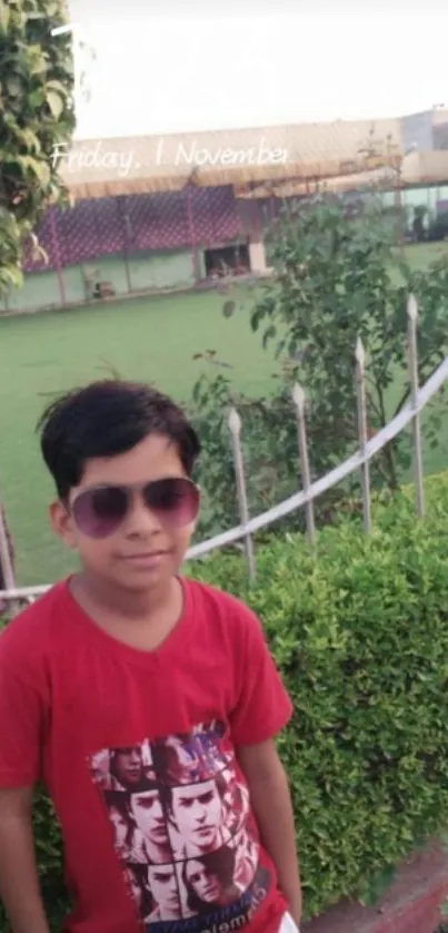 Wallpaper of a child wearing sunglasses in a garden with a green background.