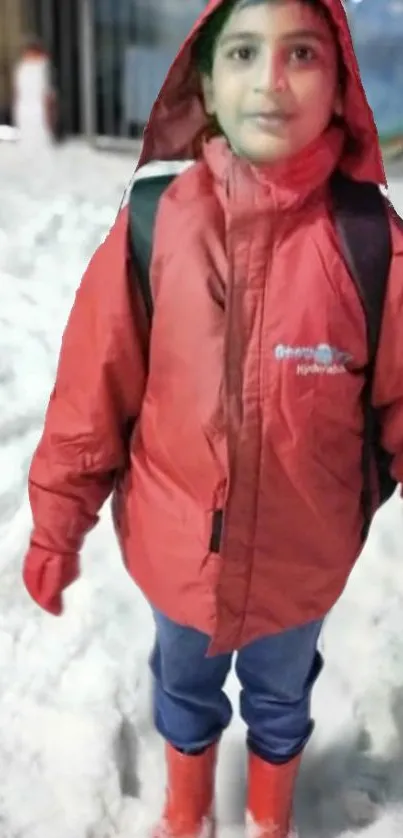 Child in a red jacket standing in the snow.