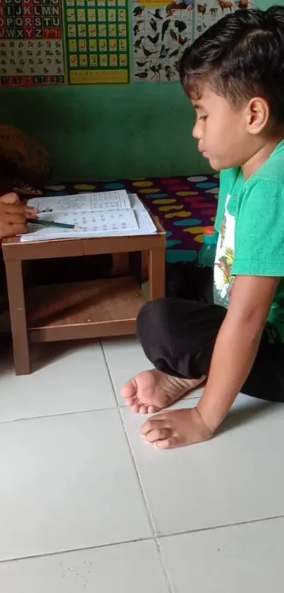 Child sitting on floor, learning from a book with a teacher at home.