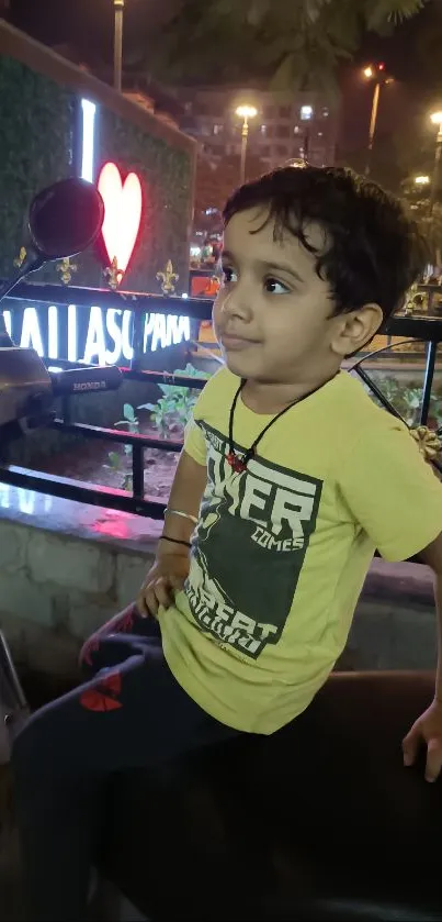 Child sitting on a scooter at night in urban setting.