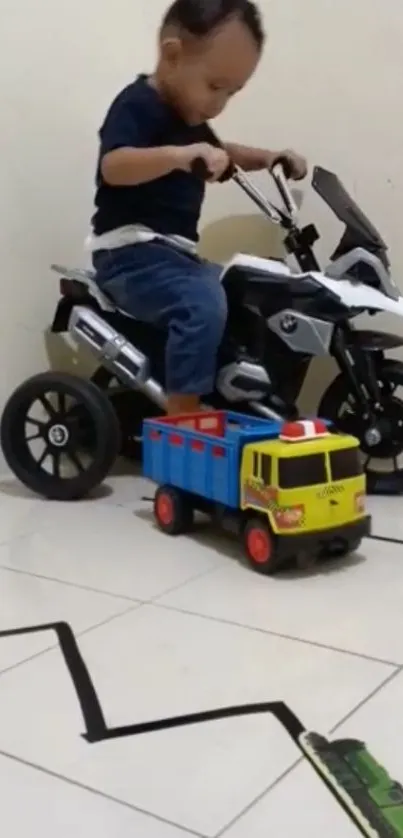 Child riding a toy motorcycle indoors with a colorful toy truck nearby.