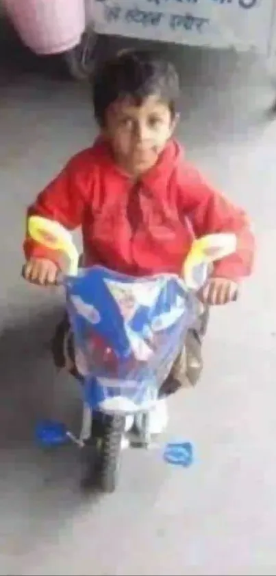 Small child in red jacket rides a toy motorcycle indoors.