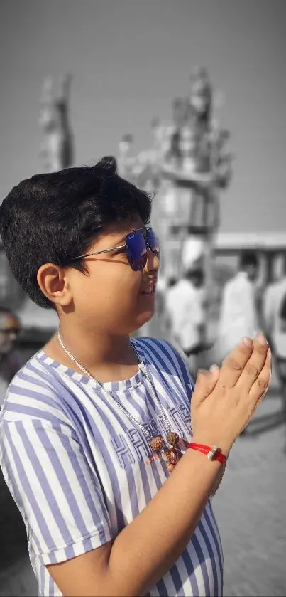 Child praying in front of statue with blue and gray tones, enhancing spirituality.