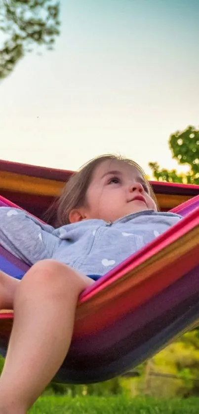 Child relaxing in a colorful hammock outdoors.