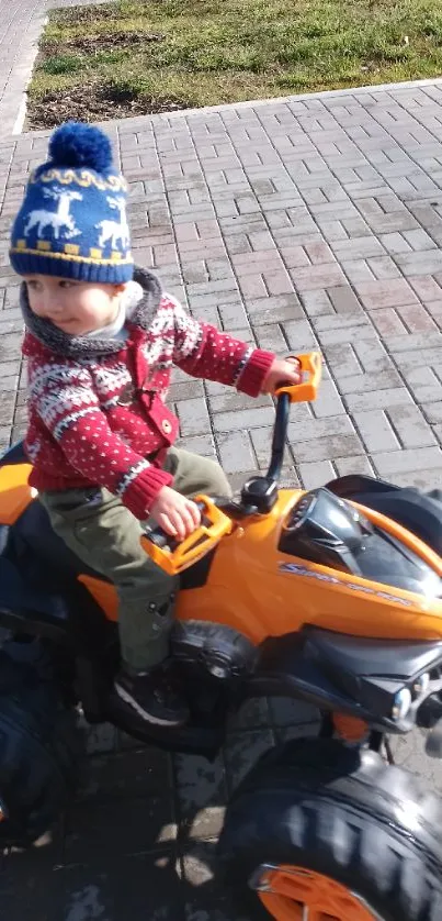 Child on a toy ATV enjoying a sunny day outdoors.