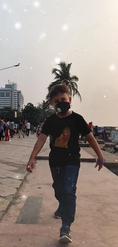 Boy wearing a mask, walking along a city waterfront at sunset.