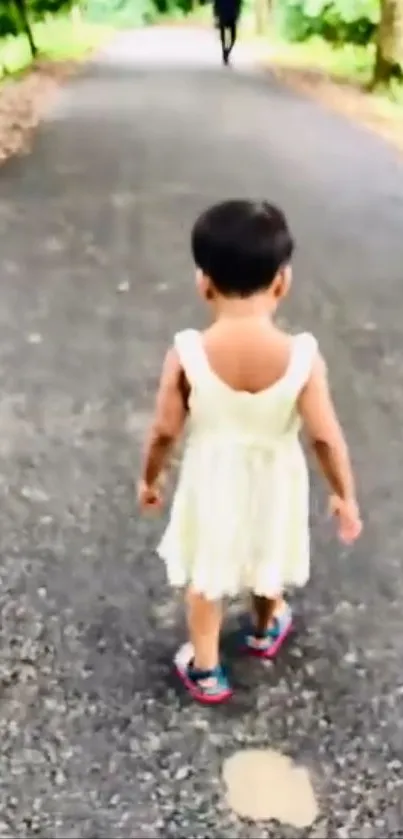 Child in white dress walking on forest path.