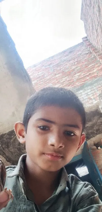 Boy holding a bird in a rustic brick setting.