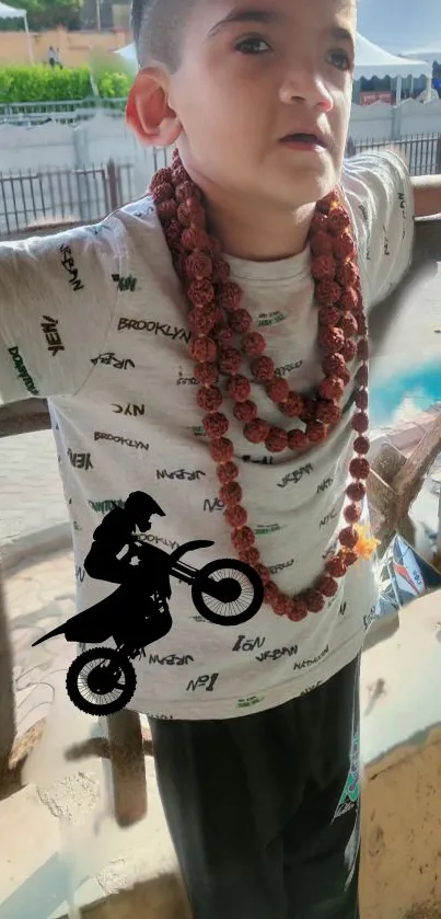 Child wearing necklaces with motorbike silhouette design in urban background.