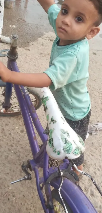 Child standing by a purple bicycle on a street.