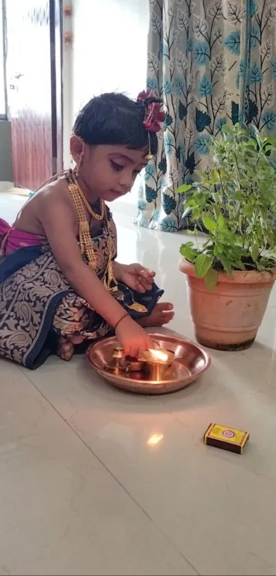 Child in traditional attire performing a ritual with a diya and plant.