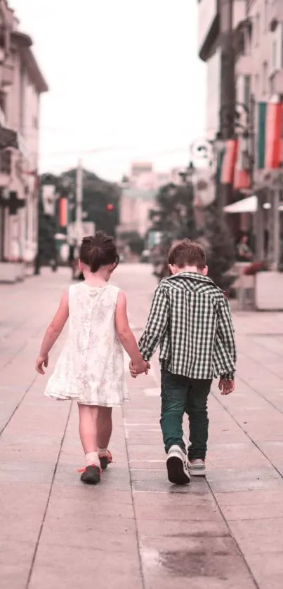 Two children walking hand in hand down a city street.