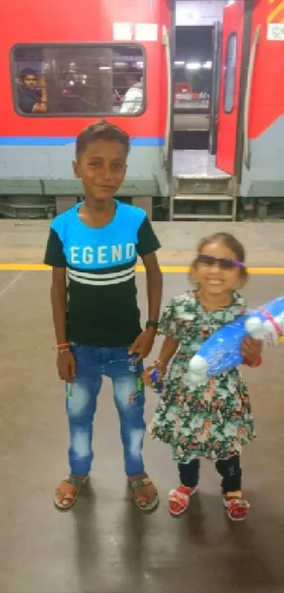 Two kids smiling at a vibrant train station background.