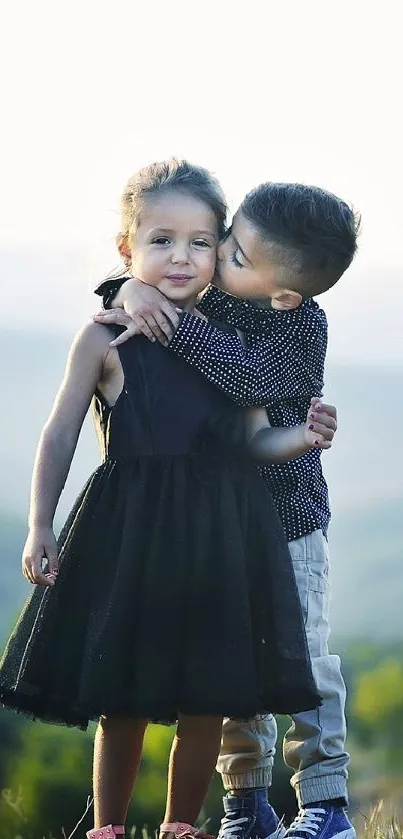 Children embracing in a sunlit, scenic landscape with hills and greenery.