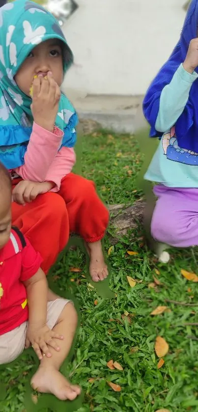 Three children enjoying corn in a grassy outdoor setting.