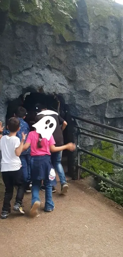 Children exploring a cave entrance with greenery and rocky textures.