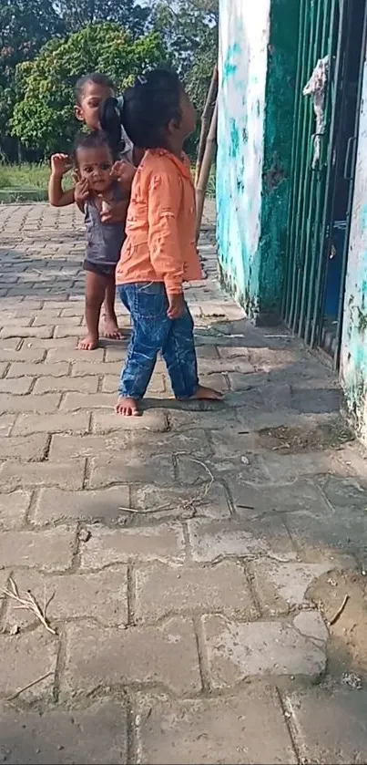 Kids playing outside near a green gate.