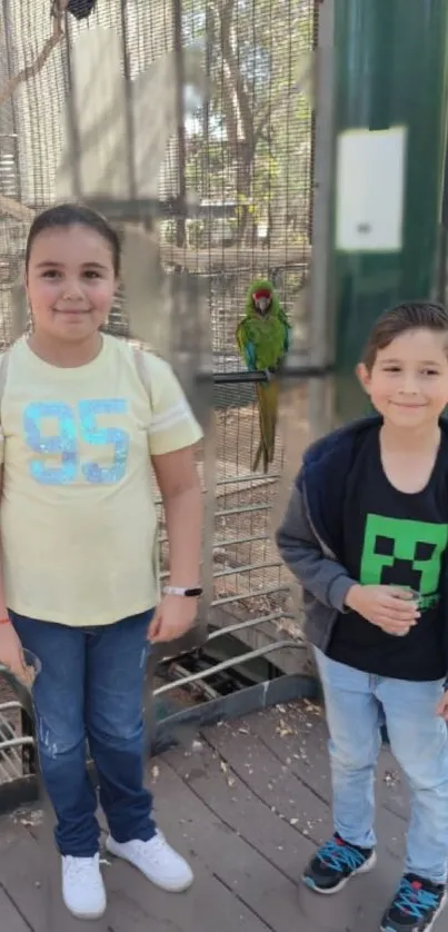 Children at a bird exhibit with green parrot.