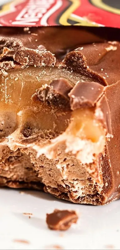 Close-up of a chocolate bar with caramel filling and candy pieces.