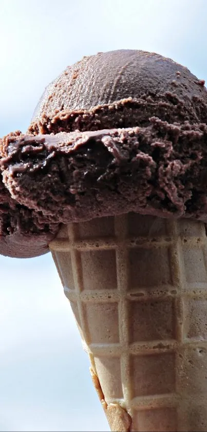 Chocolate ice cream cone with blue sky background.