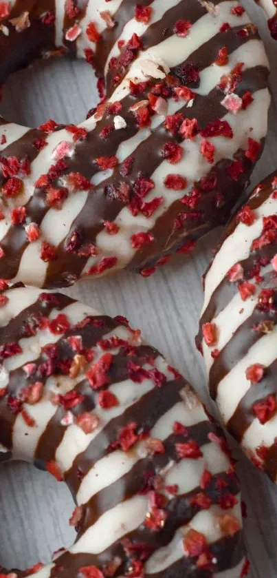 Chocolate donuts with white icing and strawberry sprinkles.