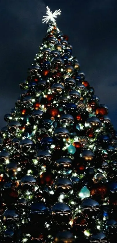 Christmas tree with lights and ornaments against a dark night sky.