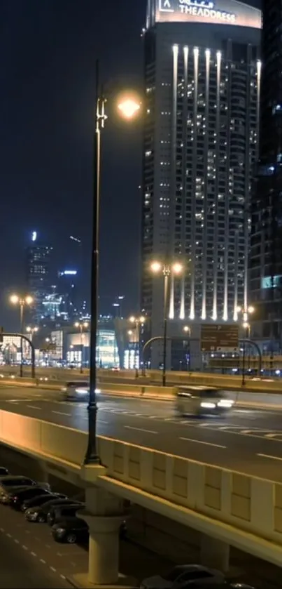 Night view of a city skyscraper and highway with illuminated lights.