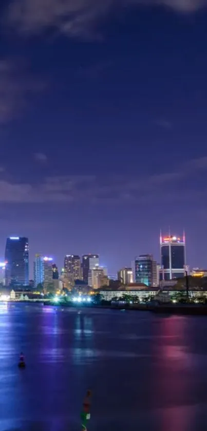 Vibrant city skyline at night with river reflections and glowing urban lights.