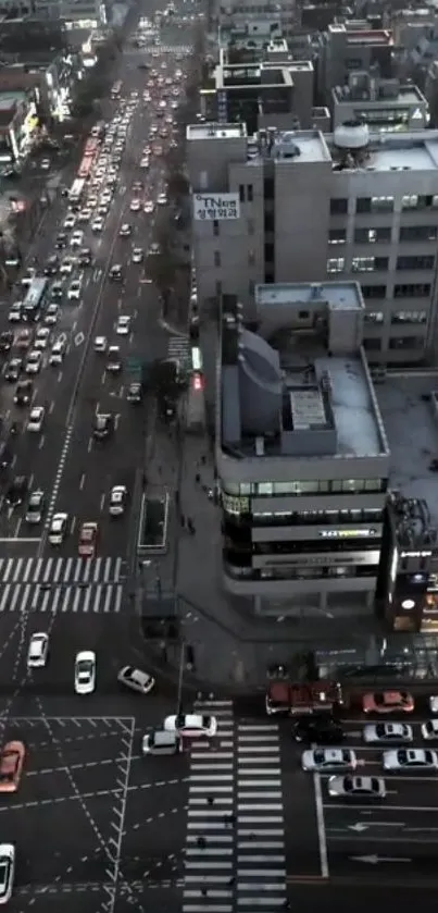 Aerial view of a bustling city street at dusk with headlights and skyscrapers.