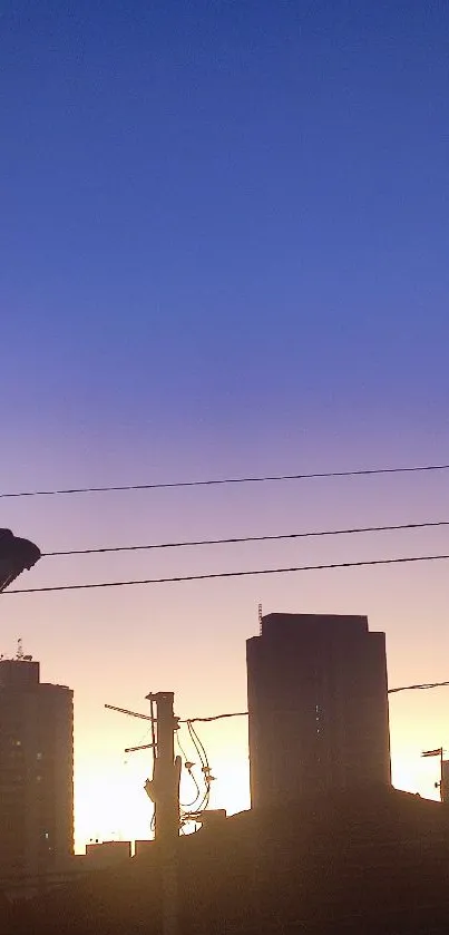 Silhouette of city buildings against a vibrant sunset sky with purple and orange hues.