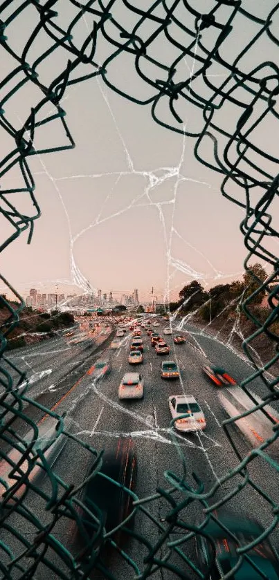 Cityscape through a fence with highway and skyline in the background at sunset.
