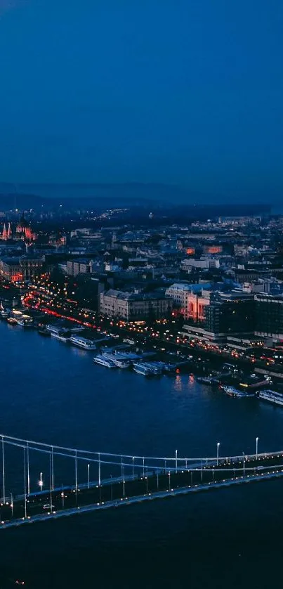 Aerial view of a city lit beautifully at night with a prominent bridge.