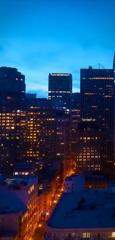 City skyline at dusk with vibrant blue sky and illuminated buildings.