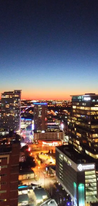 City skyline at dusk with illuminated buildings and a vibrant twilight sky.