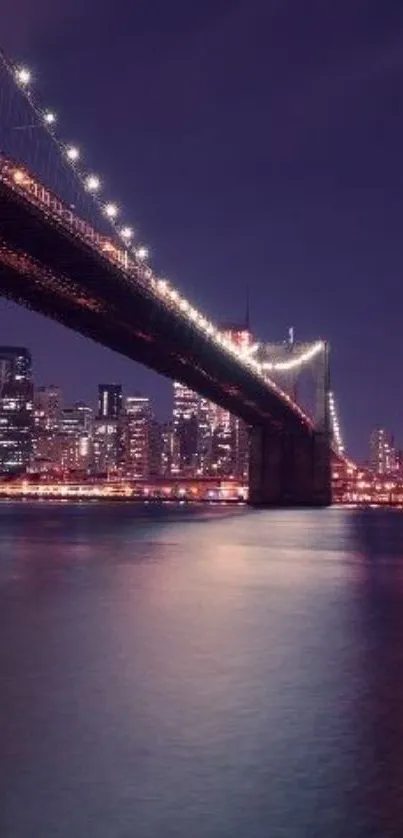 Brooklyn Bridge at night with glowing city lights reflecting on water.