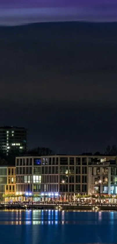 Night cityscape with reflections on water and illuminated buildings.