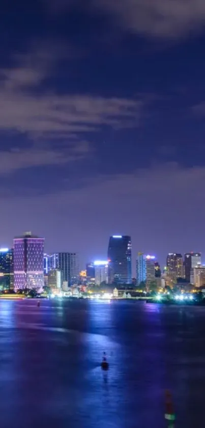 Night cityscape with illuminated skyline and water reflections.